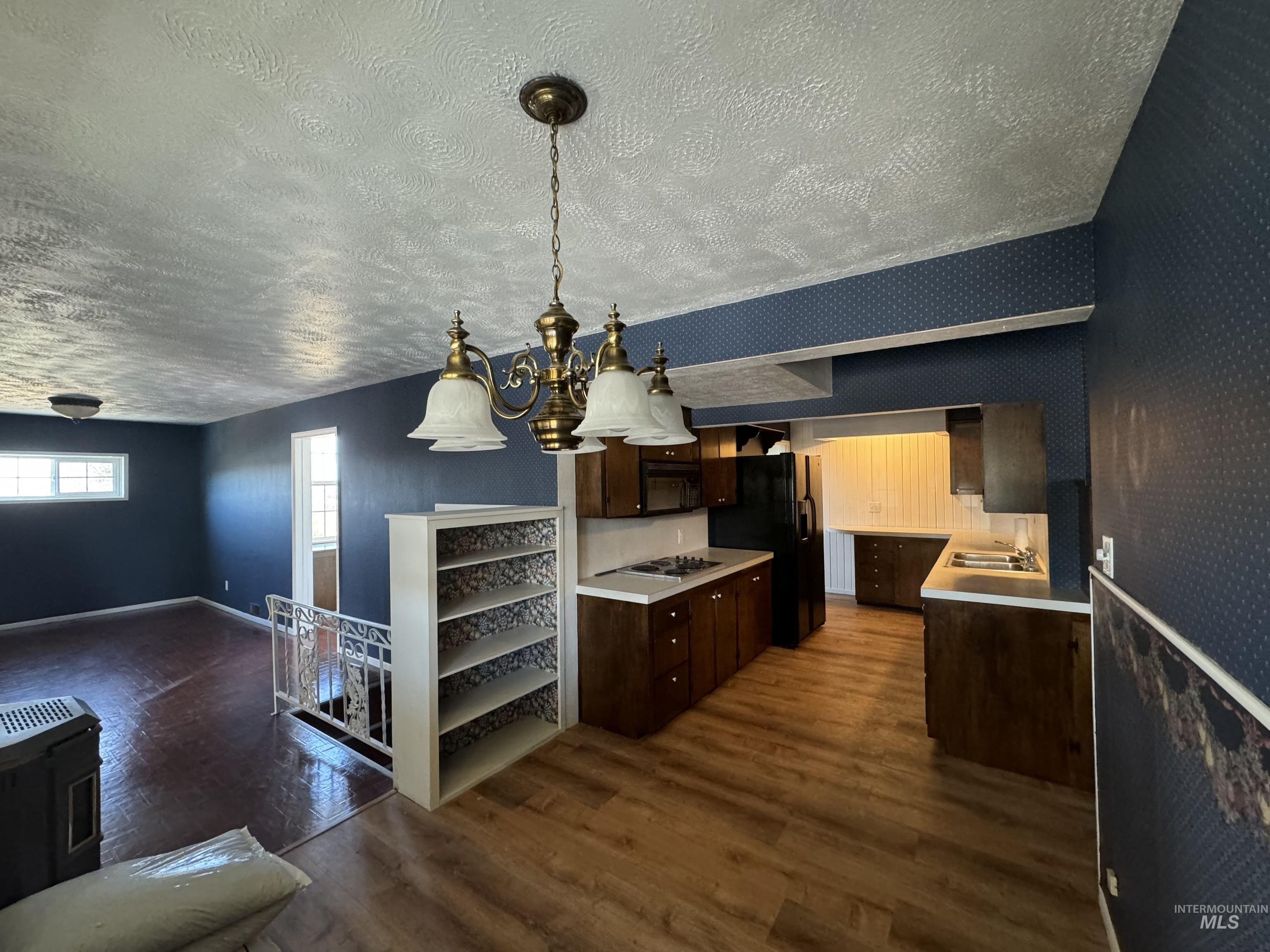 729 Morgan Avenue Ontario, OR 97914 - Photo 11 of 49 Kitchen with a textured ceiling, dark brown cabinets, dark wood-type flooring, light countertops, and wallpapered walls