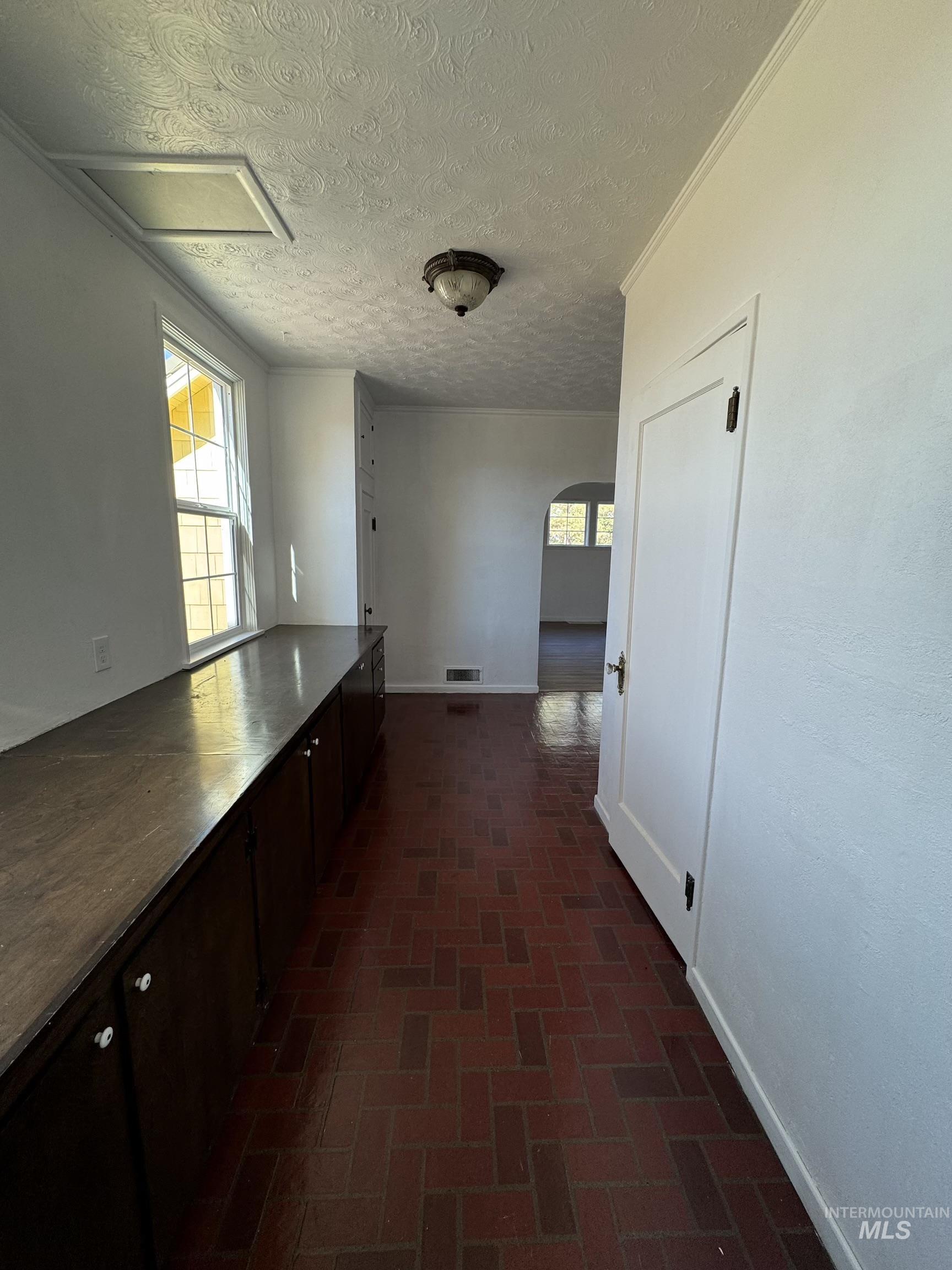 729 Morgan Avenue Ontario, OR 97914 - Photo 21 of 49 Corridor featuring arched walkways, brick patterned floors, and a textured ceiling