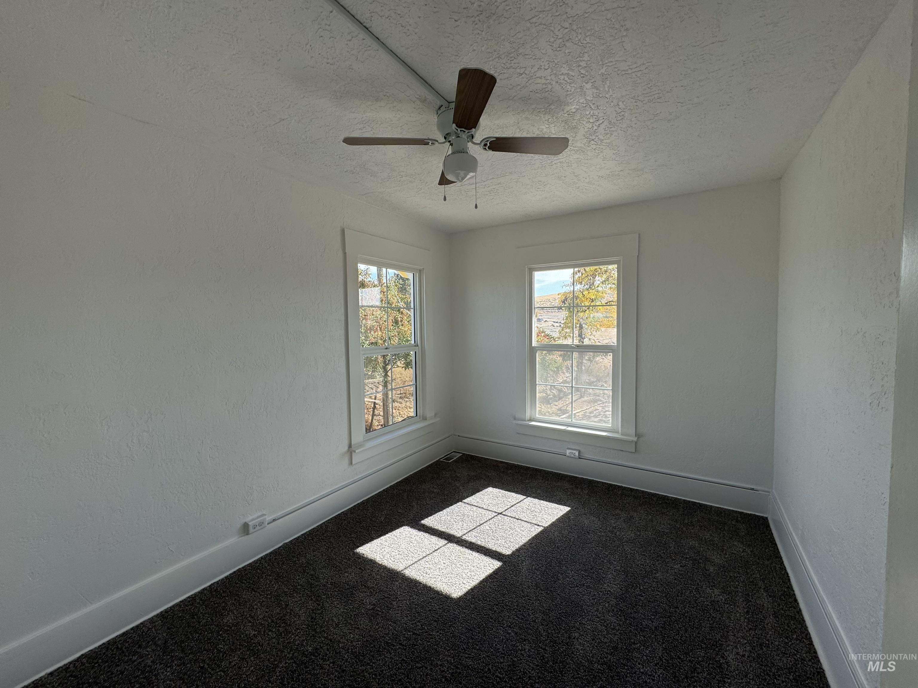 729 Morgan Avenue Ontario, OR 97914 - Photo 42 of 49 Spare room with a textured ceiling, dark carpet, ceiling fan, and a textured wall