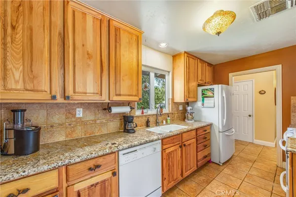 a kitchen with stainless steel appliances granite countertop a sink dishwasher and a refrigerator with wooden cabinets