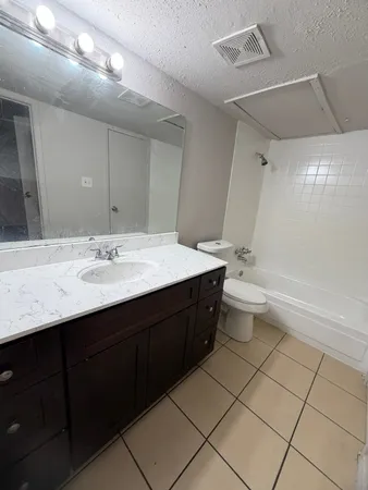 a spacious bathroom with a double vanity sink toilet mirror and bathtub