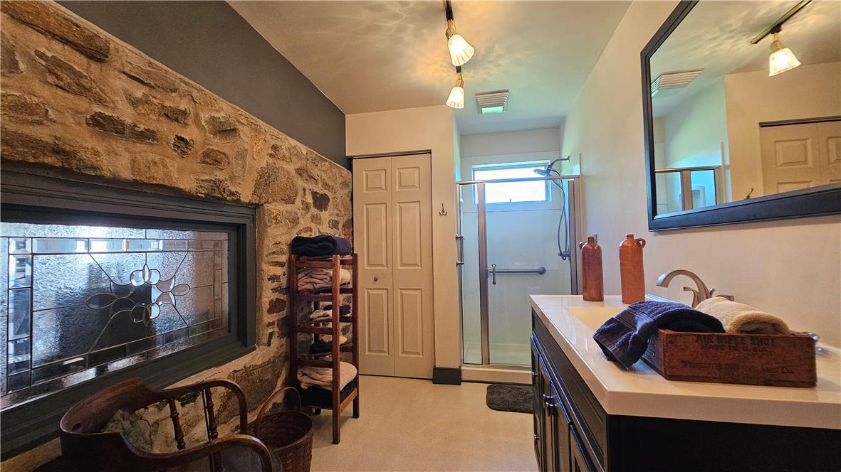 585 Buttermilk Road Hellertown, PA 18055 - Photo 23 of 82 A quaint bathroom with a unique stone accent wall and a glass-enclosed shower.