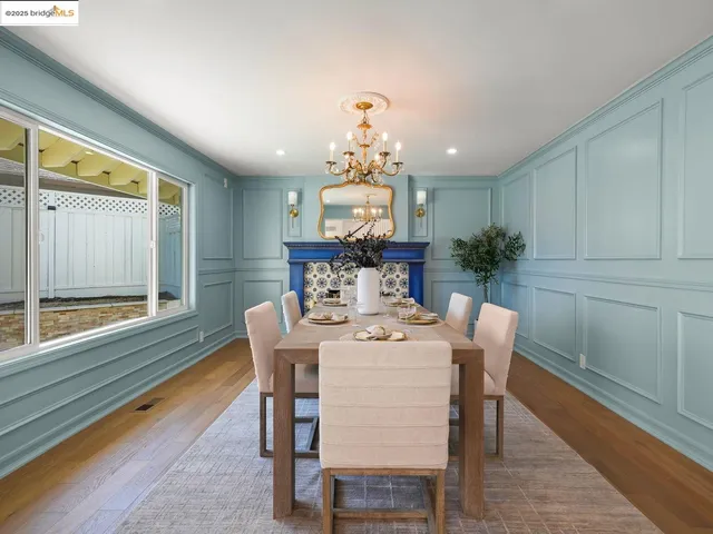 a dining room with furniture a large window and wooden floor
