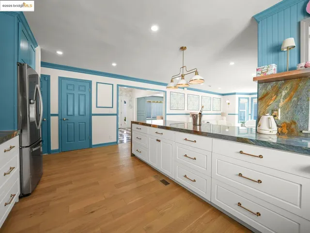 a large kitchen with stainless steel appliances a large counter top a sink and a refrigerator