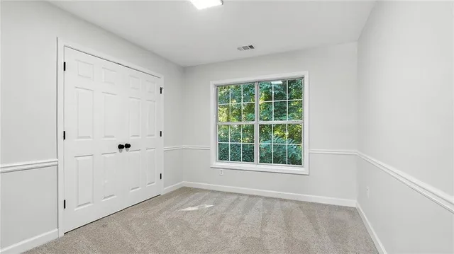 an empty room with chandelier fan and windows
