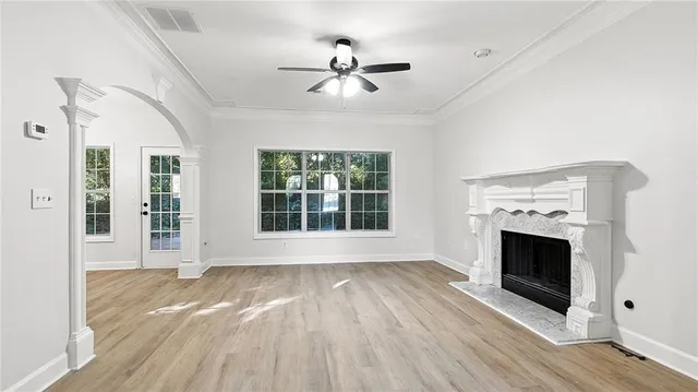 a view of an empty room with wooden floor fireplace and a window