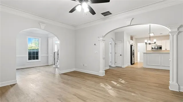 a view of an empty room with wooden floor and a kitchen