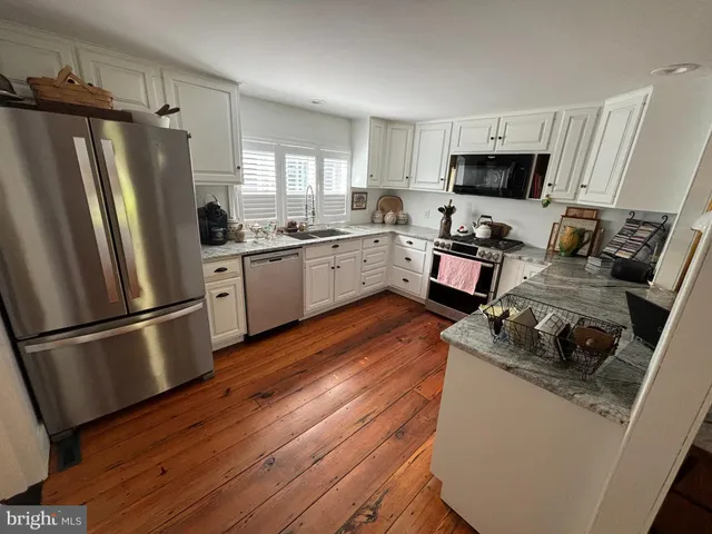 a kitchen with a refrigerator a stove top oven a sink dishwasher and wooden floor