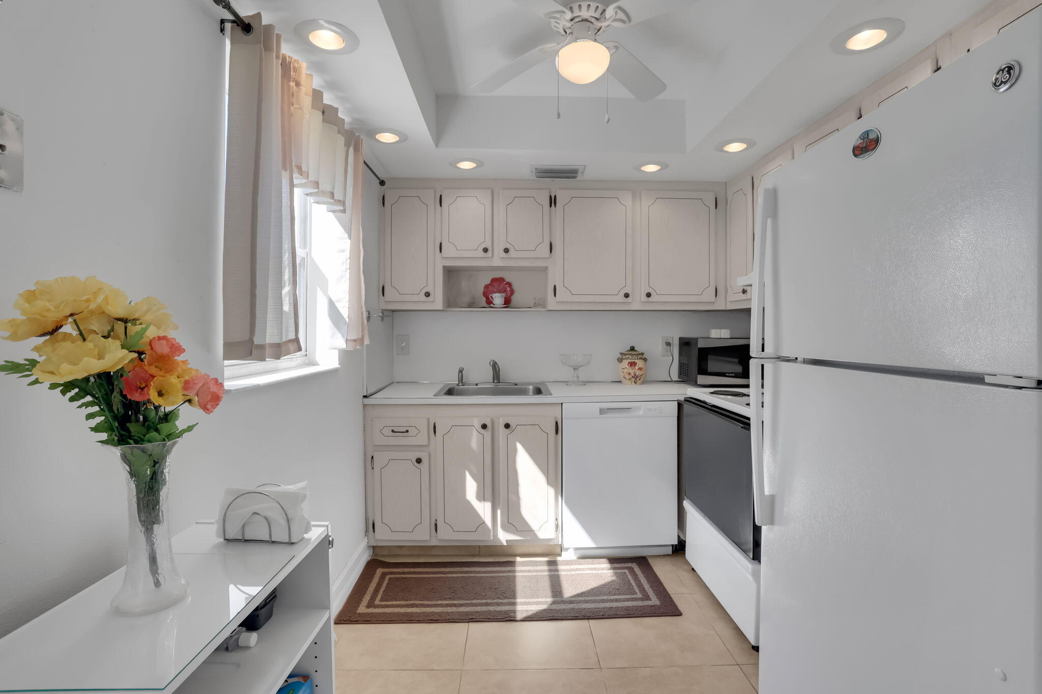 152 Tuscany Lane, Unit C Delray Beach, FL 33446 - Photo 13 of 40 a kitchen with a refrigerator sink and white cabinets
