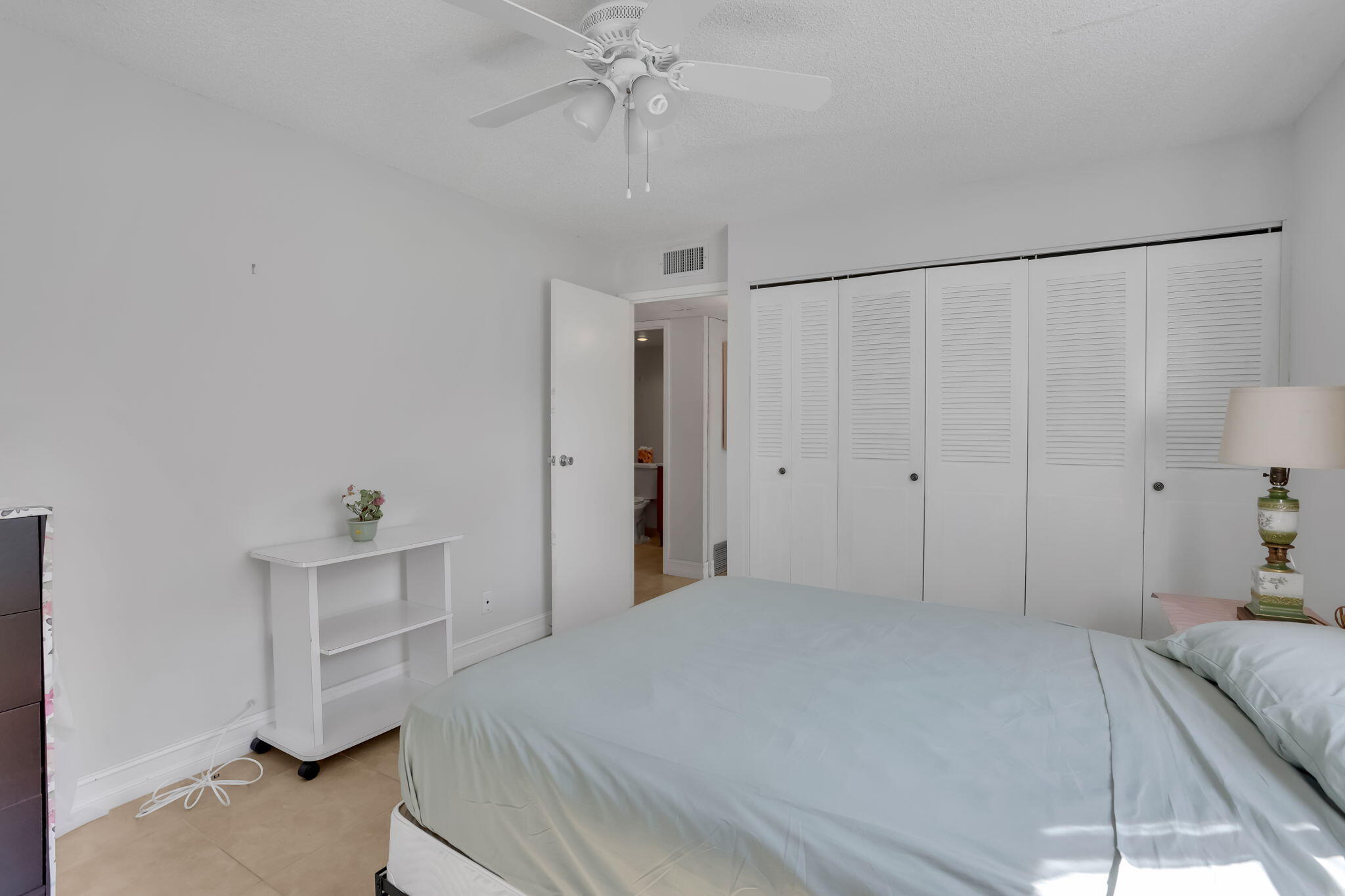 152 Tuscany Lane, Unit C Delray Beach, FL 33446 - Photo 18 of 40 a bedroom with a bed and a chandelier