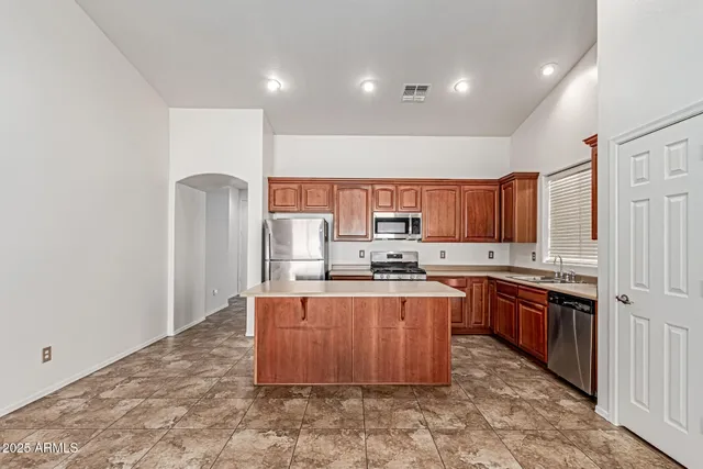 a kitchen with stainless steel appliances granite countertop a stove top oven a sink and a refrigerator