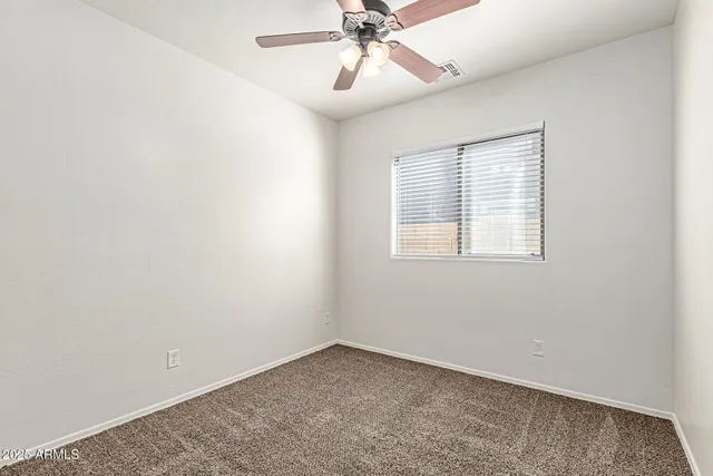an empty room with a window and a fan