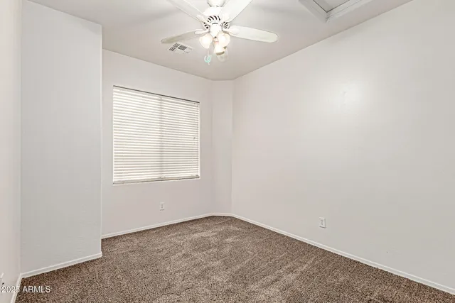 an empty room with a window and a ceiling fan