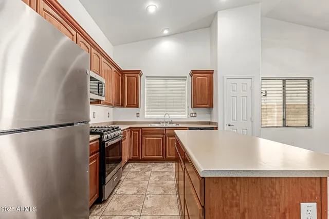 a large kitchen with stainless steel appliances granite countertop a refrigerator a sink dishwasher a stove with wooden floor