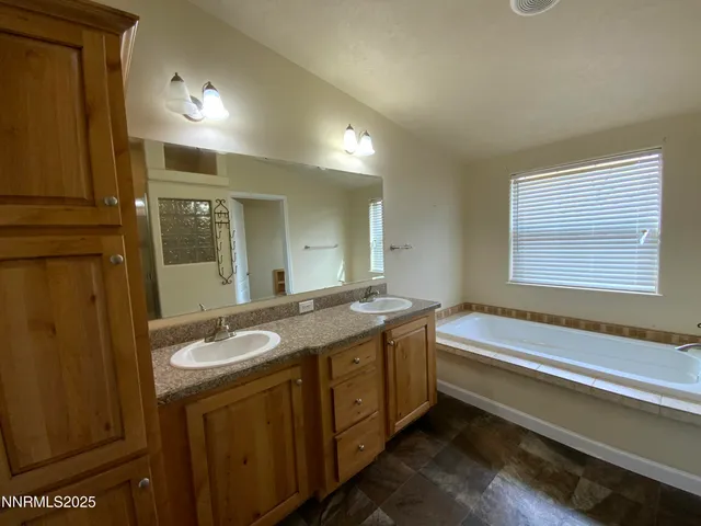 a bathroom with a granite countertop sink and a bathtub