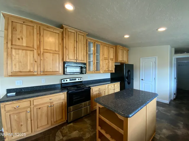 a kitchen with stainless steel appliances granite countertop a stove a refrigerator a sink a microwave and island