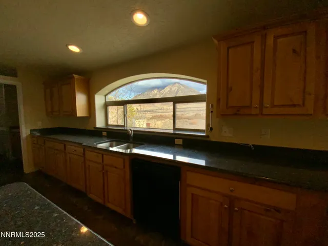 a kitchen with granite countertop white cabinets sink and window