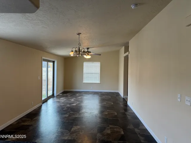 an empty room with wooden floor chandelier and windows