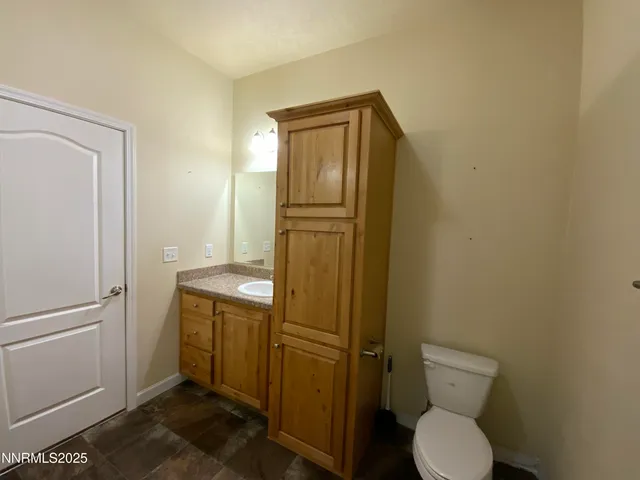 a bathroom with a granite countertop toilet and a sink