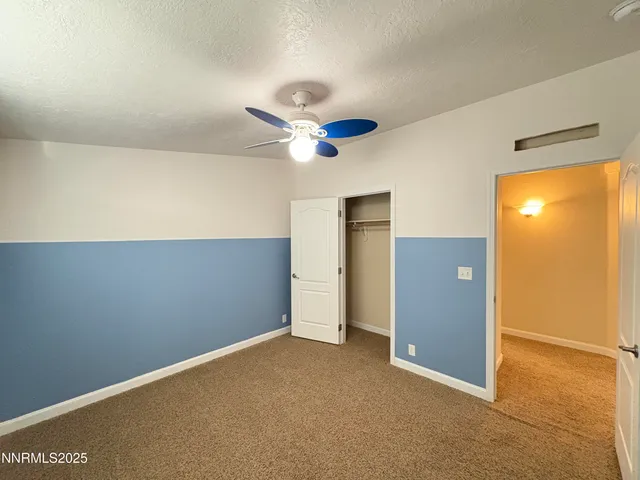 an empty room with closet and ceiling fan