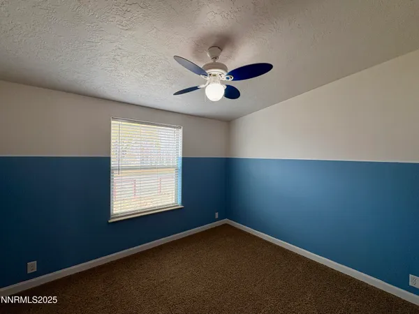 an empty room with a window and a fan