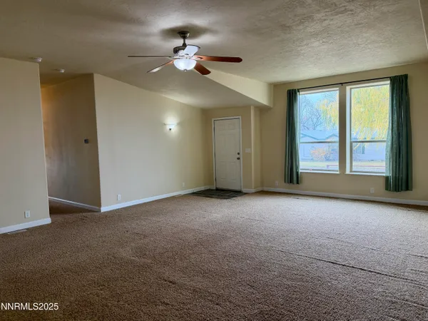 a view of an empty room with a chandelier fan