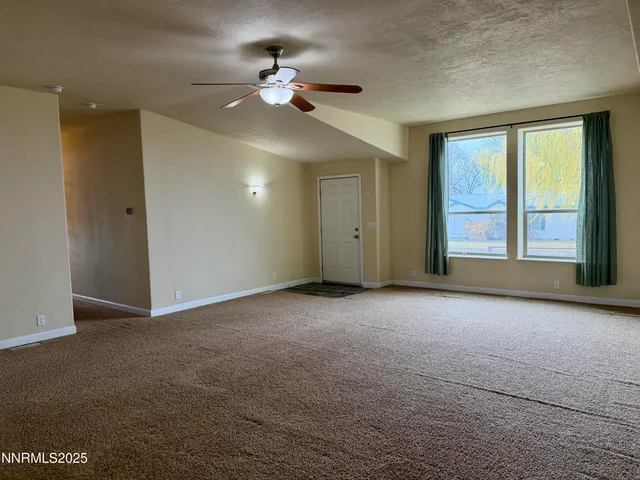 a view of an empty room with a chandelier fan