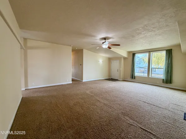 a view of an empty room with a chandelier fan