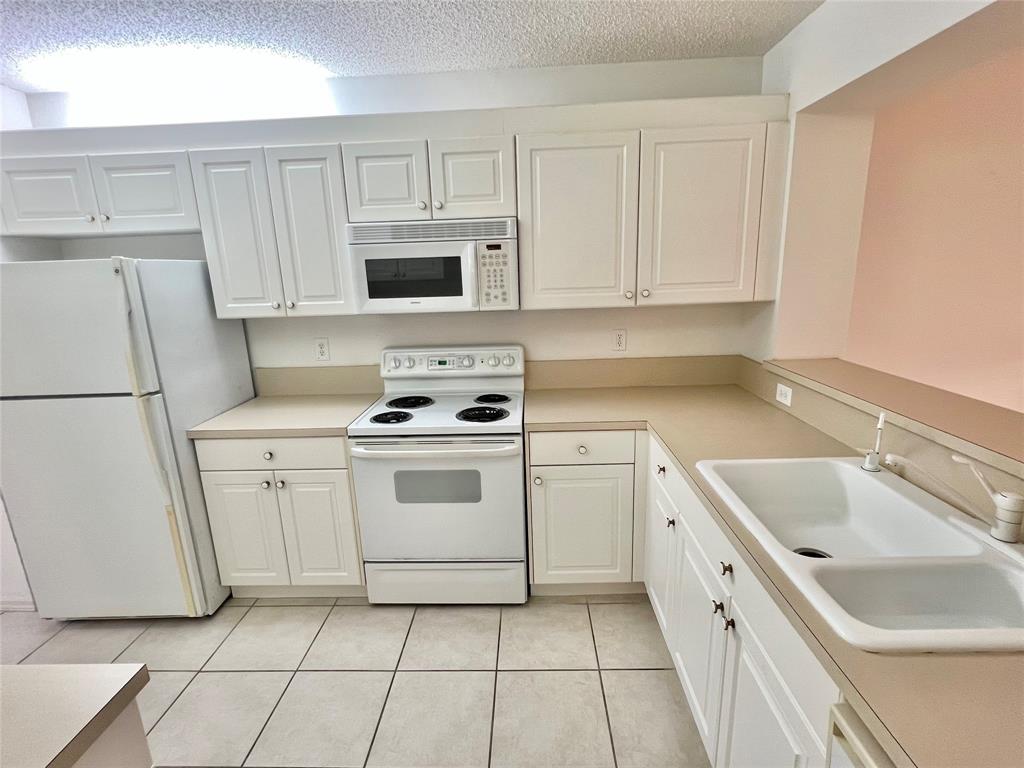 7763 Southampton Terrace, Unit 411 Tamarac, FL 33321 - Photo 3 of 33 a kitchen with white cabinets sink and white appliances