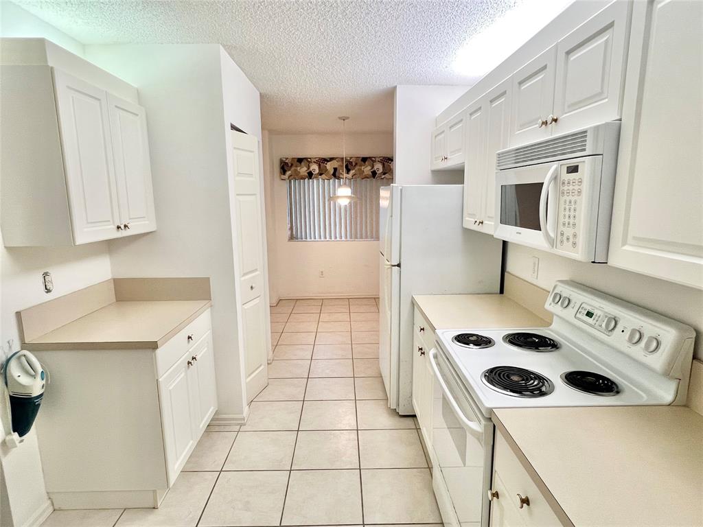 7763 Southampton Terrace, Unit 411 Tamarac, FL 33321 - Photo 5 of 33 a kitchen with a stove a sink and a refrigerator