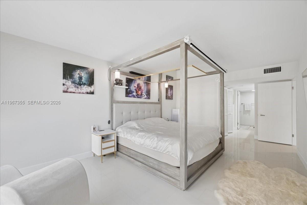 1915 Brickell Avenue, Unit 801 Miami, FL 33129 - Photo 18 of 37 a white bed sitting in a bedroom next to a cabinet