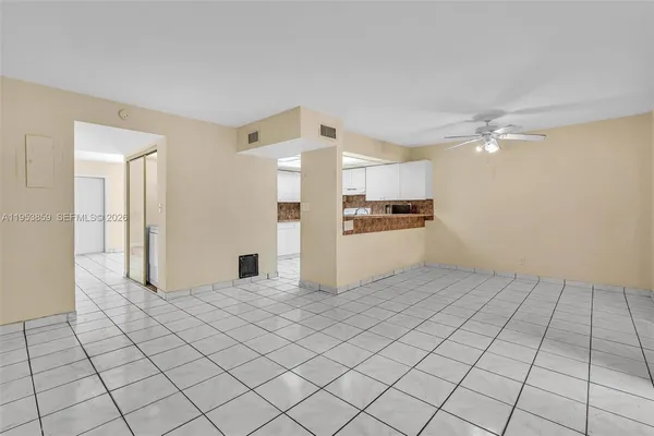 an empty room with chandelier fan and windows
