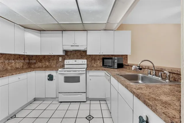 a kitchen with granite countertop white cabinets and white appliances