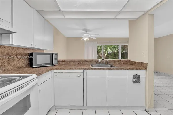 a view of a kitchen with white cabinets and a window