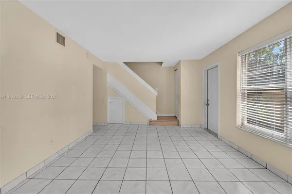 a view of an empty room with window and stairs