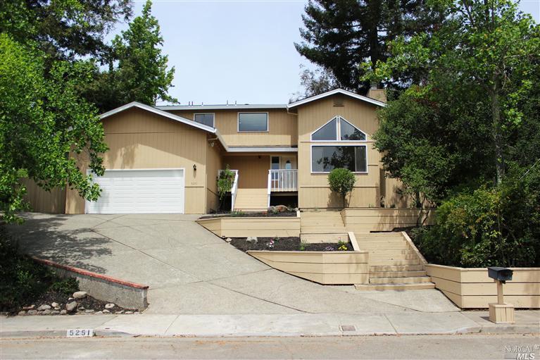 a view of a house with a yard and large tree