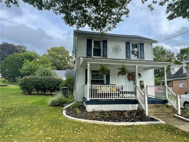 a view of a house with a small yard plants and large tree