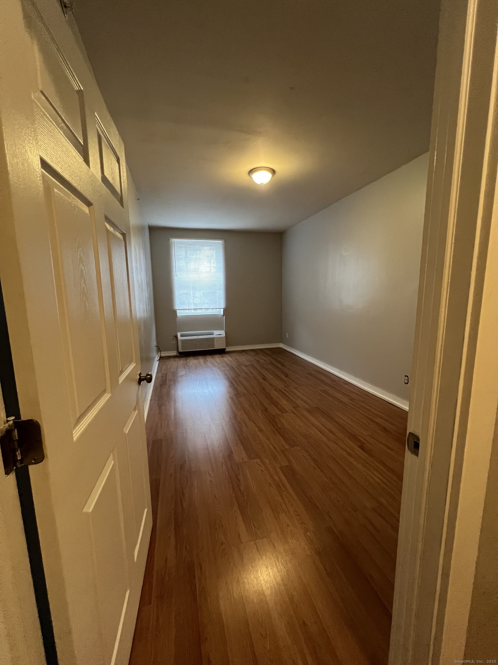 385 Putnam Avenue, Unit 18 Hamden, CT 06517 - Photo 11 of 14 an empty room with wooden floor and windows