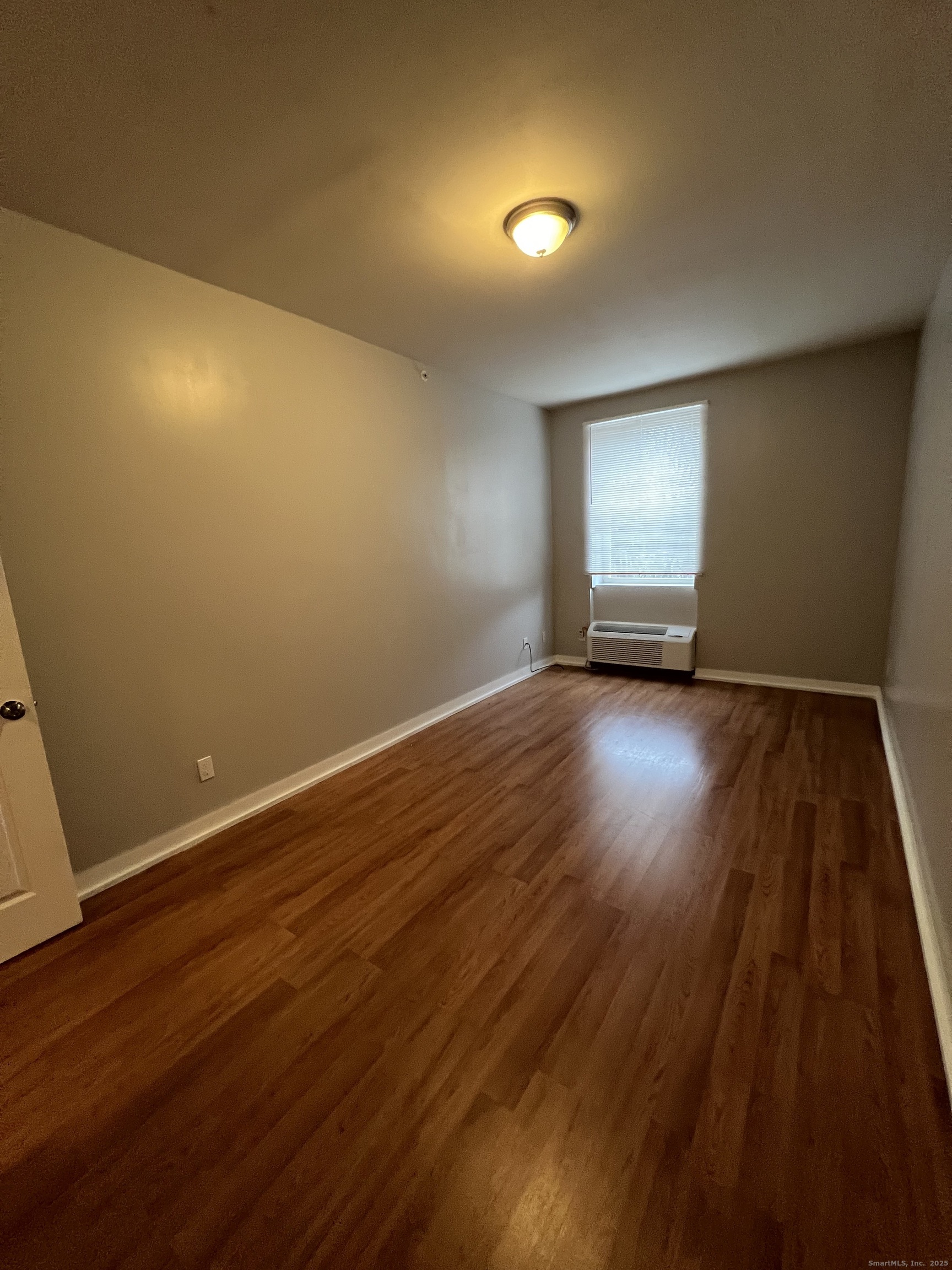 385 Putnam Avenue, Unit 18 Hamden, CT 06517 - Photo 12 of 14 an empty room with wooden floor and windows