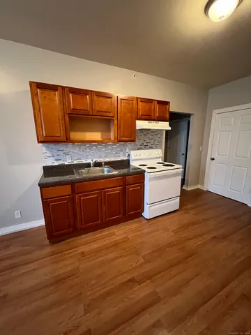 a kitchen with a stove and wooden floor