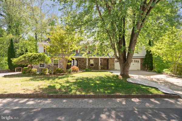 a front view of a house with a yard and large tree