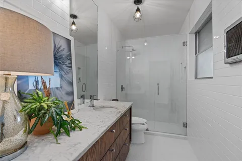 a bathroom with a granite countertop sink a toilet and shower