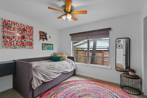 a bedroom with a bed a dresser and a large window