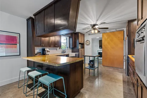 a room with stainless steel appliances kitchen island granite countertop furniture and a chandelier