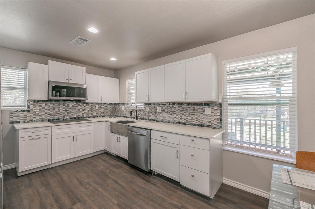 7612 Sommerville Place Road Fort Worth, TX 76135 - Photo 23 of 37 a kitchen with granite countertop white cabinets and white appliances