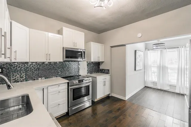 a view of a kitchen with refrigerator and wooden floor