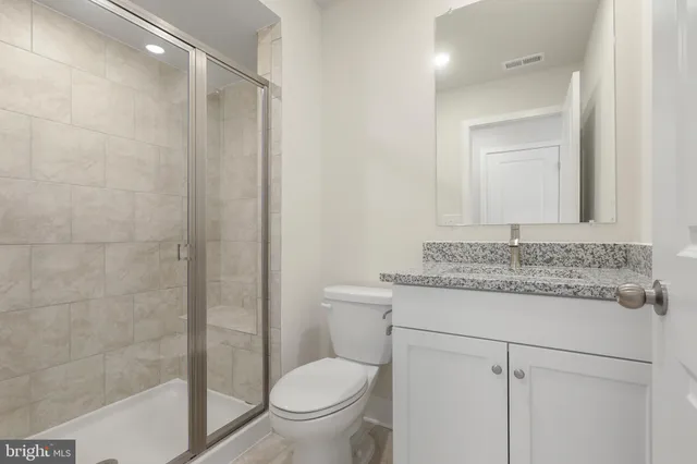 a bathroom with a granite countertop sink toilet and shower