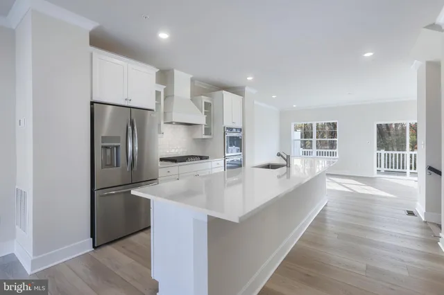 a large kitchen with stainless steel appliances granite countertop a refrigerator and a sink