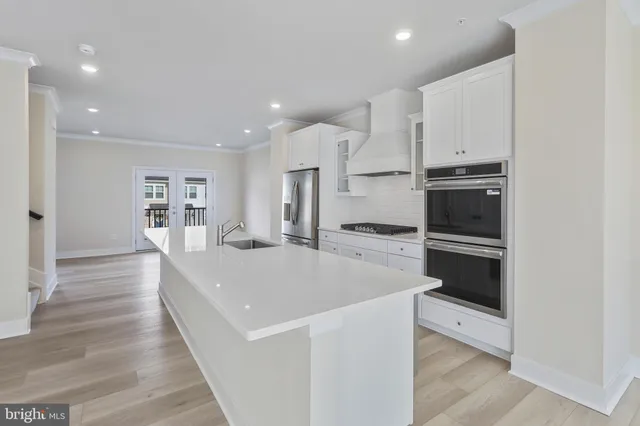 a large white kitchen with a stove top oven a sink and dishwasher