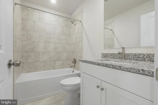 a bathroom with a granite countertop sink a toilet and bathtub